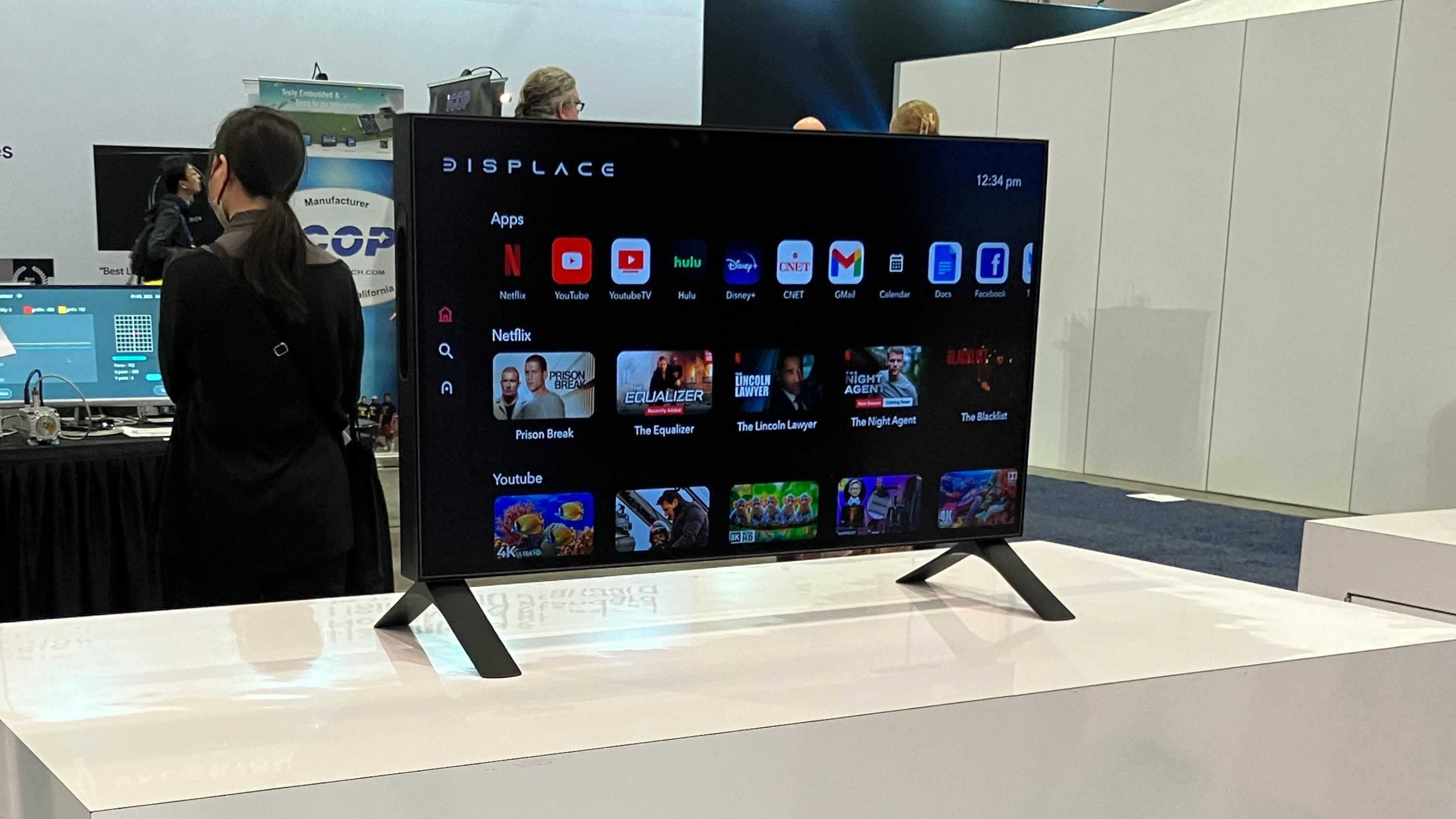 27 inç kablosuz Displace TV, CES 2025 standındaki sergi masasında duruyor. TV, akıllı platformunun ana ekranını görüntülüyor.