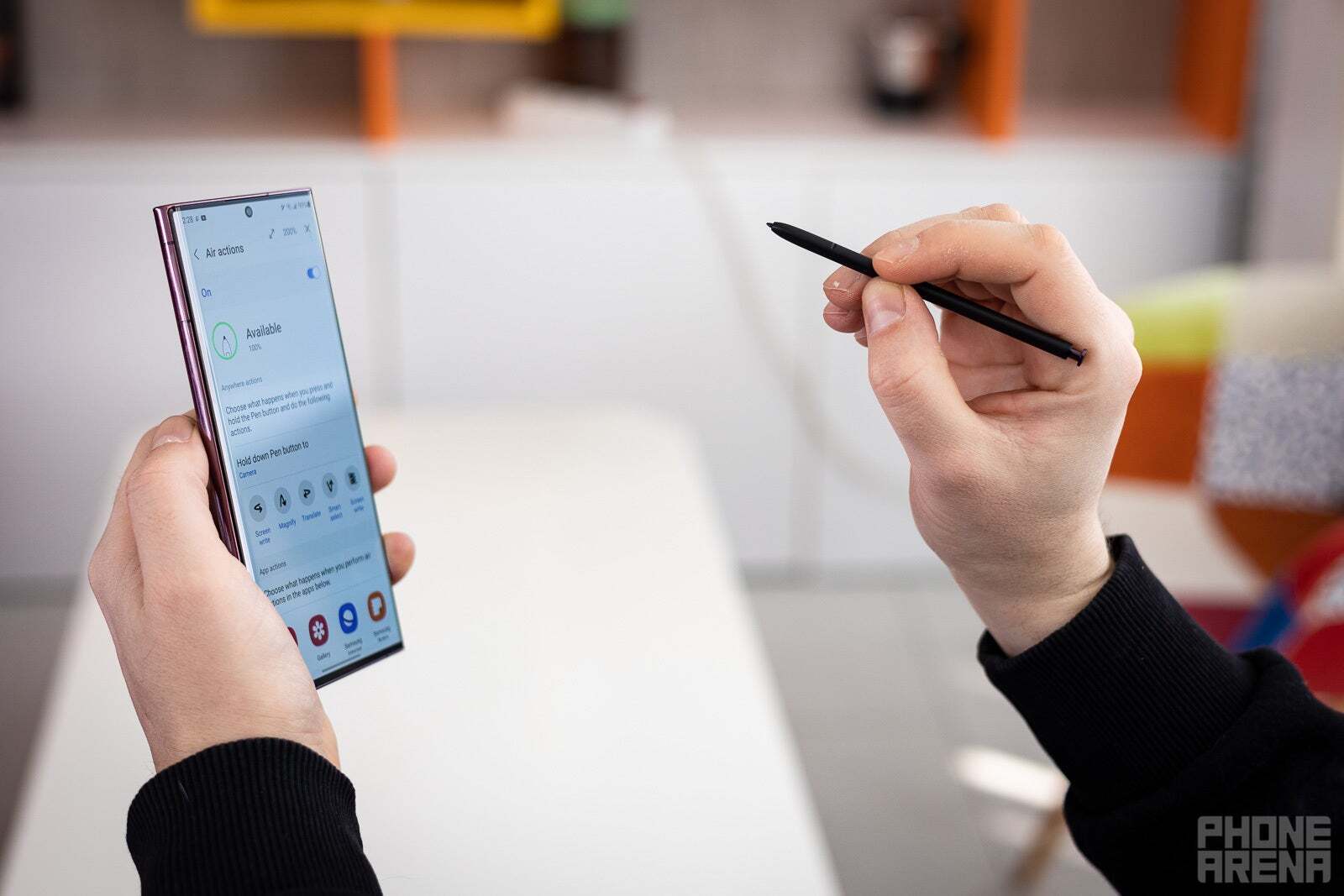 Bir elinde Galaxy S22 Ultra'yı, diğer elinde S Pen'i tutan bir kişi.