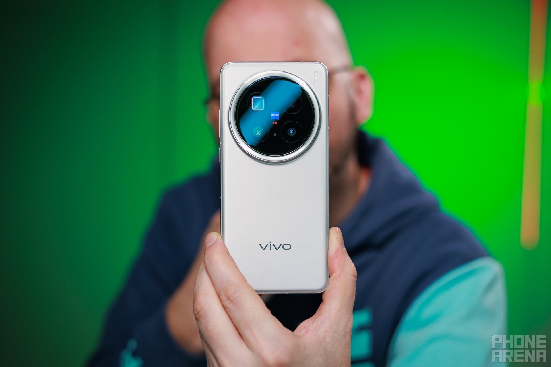 Vivo X200 Pro'nun arkasını kameraya gösteren kel bir adam.