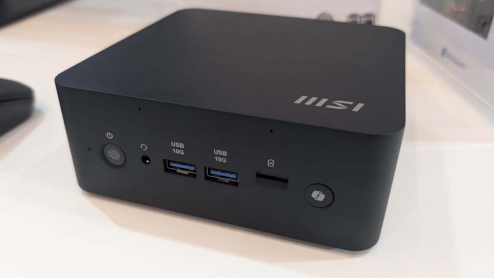 Beyaz bir masa üzerinde MSI Cubi NUC AI+ 2M'nin ön tarafı.