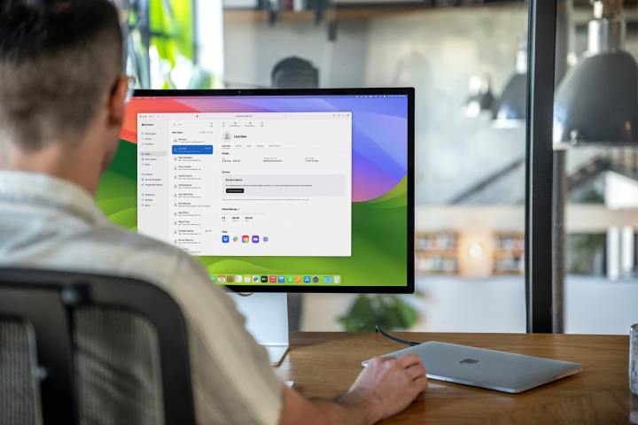 Stüdyo ekran monitörü ile Apple MacBook Air kullanan bir kişi.