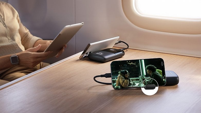 Bir kişi, telefon güç bankasında şarj olurken, telefonda bir film oynatılırken tablet kullanıyor.