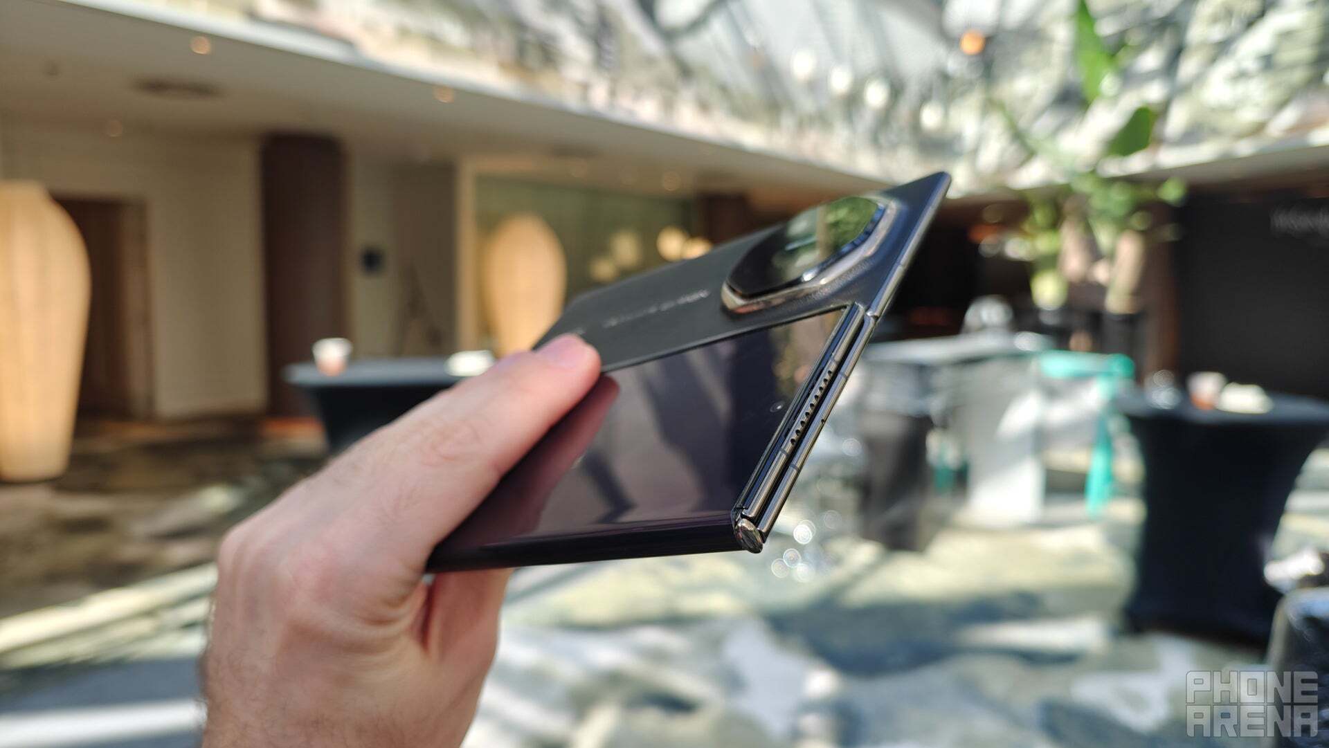 Üçe katlanabilen telefon Huawei Mate XT'yi elinde tutan bir kişi. 