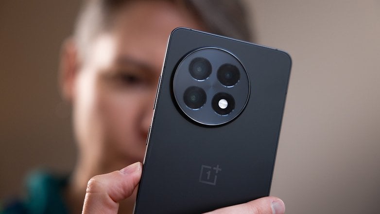 Bir kişi tarafından tutulan bir OnePlus 13R akıllı telefonun yakın çekimi yoldaşlığı gösterir.