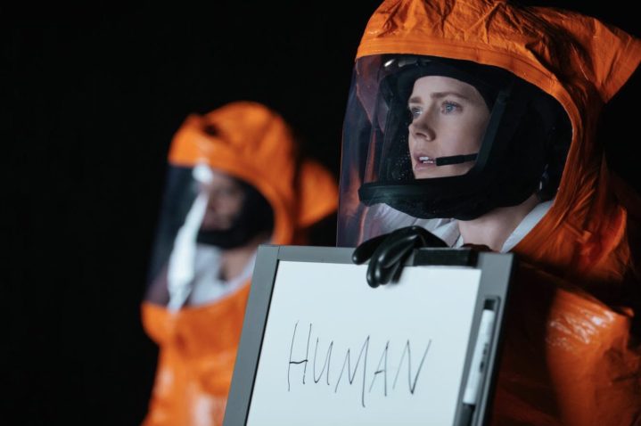 Amy Adams varışta bir beyaz tahta işareti tutuyor.