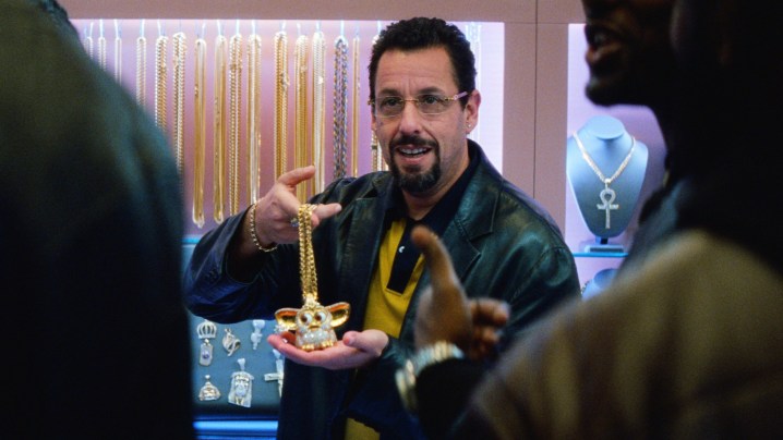 Howard Ratner rolünde Adam Sandler, kesilmemiş mücevherlerde bir parça veya mücevher tutuyor.