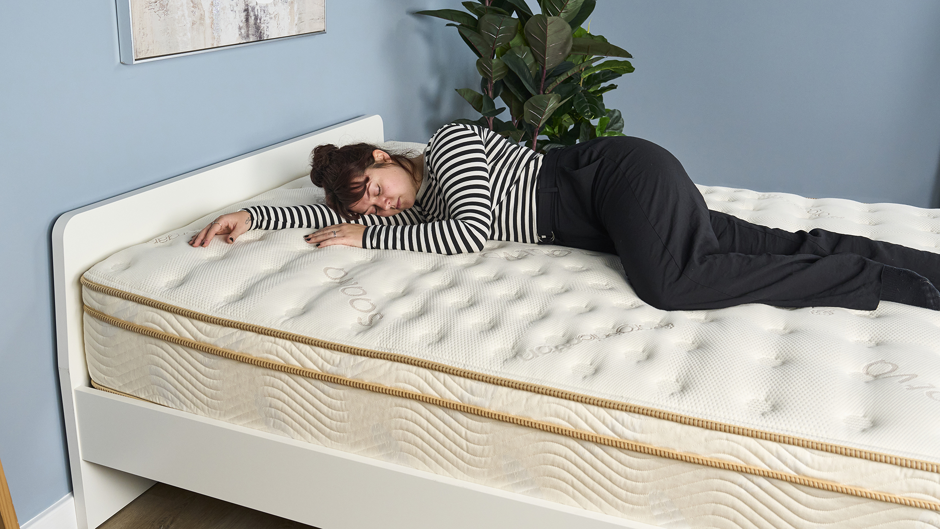 Tom'un Guide Sleep Features Editor, Sleep Studio'umuzda bir test paneli inceleme oturumu sırasında Saatva Klasik Yatakta yanında yatıyor