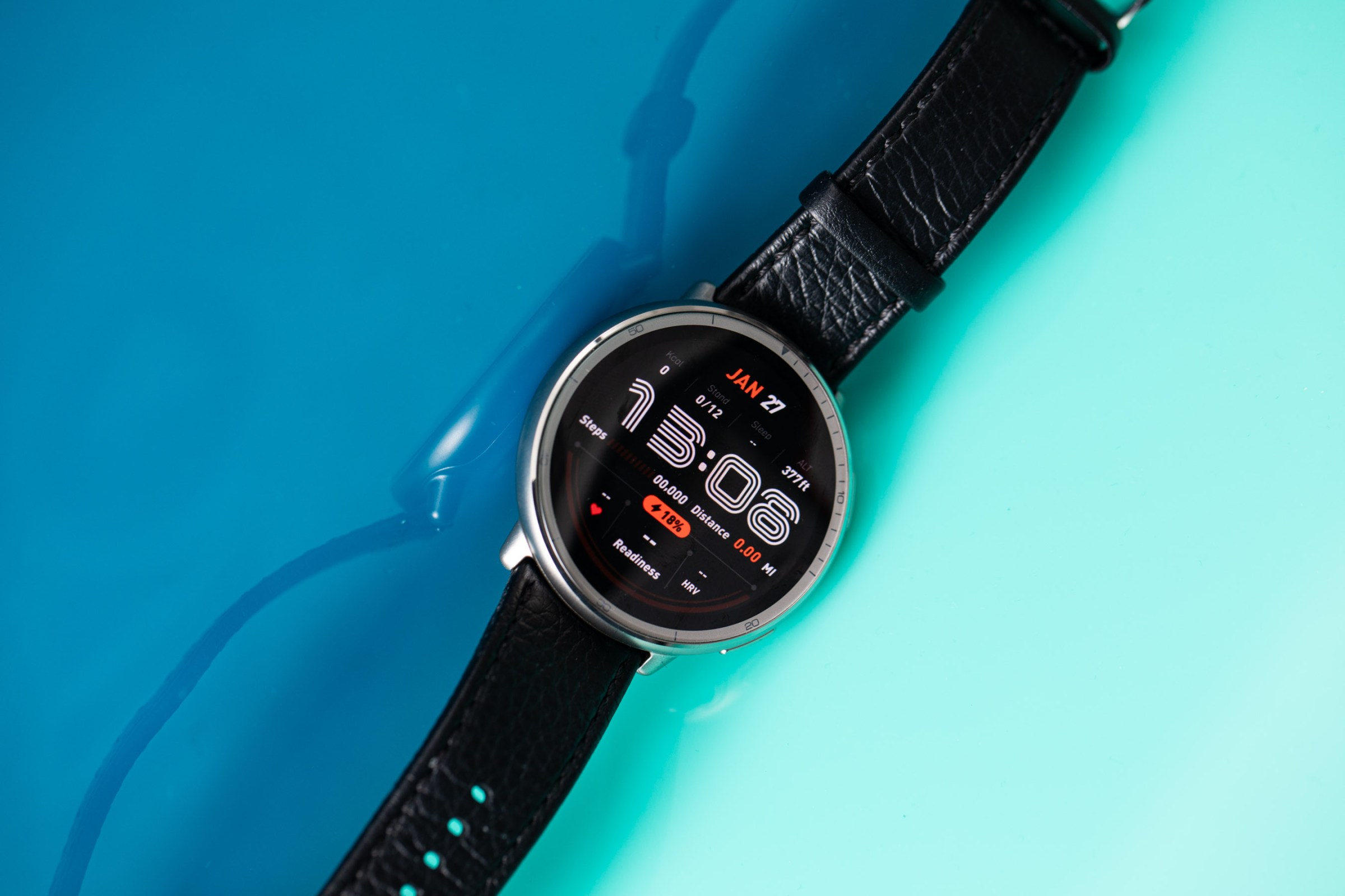 Siyah deri kayış ile Amazfit Active 2'nin açılı görünümü geri alındı. Saat, yansıtıcı bir mavi akrilik arka planın üstünde oturuyor.