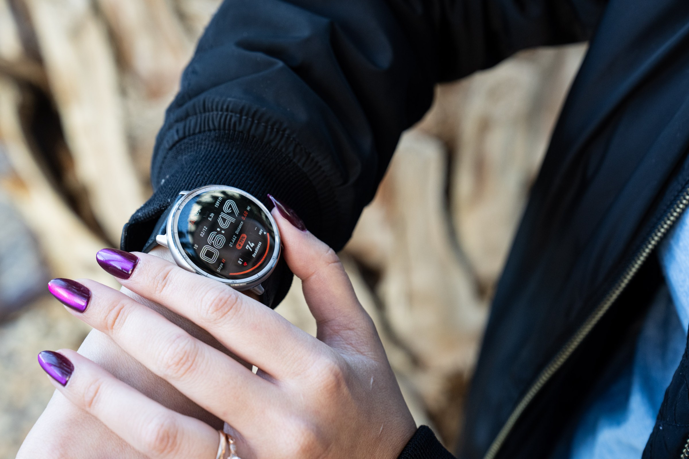 Siyah ceket ve mor tırnaklar giyerken Amazfit Active 2'yi kullanarak kıdemli gözden geçiren Victoria şarkısının yakın çekimi. Bulanık bir çöl arka planı görebilirsiniz.