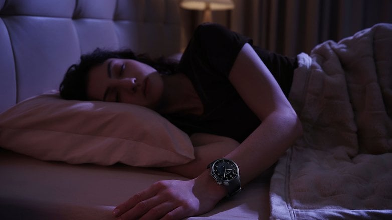 Bir kişi yatakta uyur ve bilekte OnePlus Watch 3 giyer.