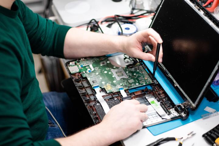 Birisi küçük bir tornavida ile bir Macbook'un içini onarıyor.