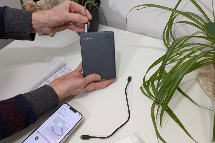 Canon, Selphy QX20 ile kısa bir USB kablosu biriktirir, ancak standart bir USB-C kablosu ve şarj cihazı ile çalışır.