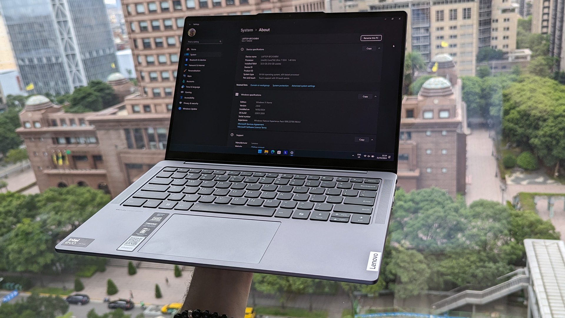 Bir pencerenin önünde tutulan Lenovo Slim 7i 14 (Gen 9) dizüstü bilgisayar.