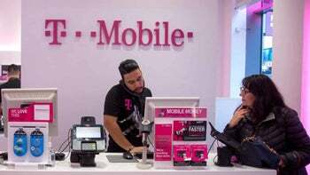 Bir T-Mobile temsilcisi, bir perakende mağazasındaki bir müşteriye yardımcı olur.
