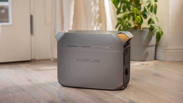 Bir bitkinin yanındaki ahşap bir zeminde gri bir EcoFlow Delta 3 artı portatif elektrik santrali.