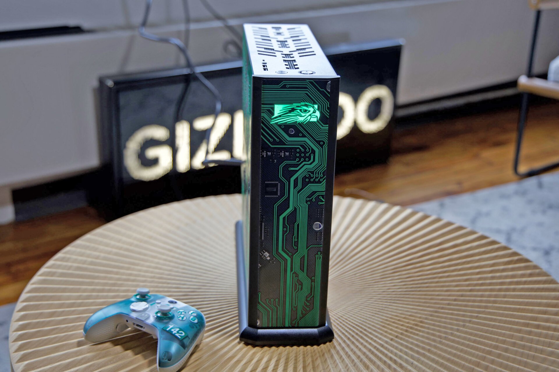 Gizmodo Sign ile Ahşap Masada Yeşil ve Beyaz Xbox Scuf Kontrolör ile Kuzeybatı Falcon Tiki'nin ön çekimi