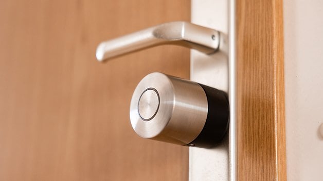 Ahşap bir kapıya monte edilmiş bir Nuki Smart Lock Pro'nun kapatılması.