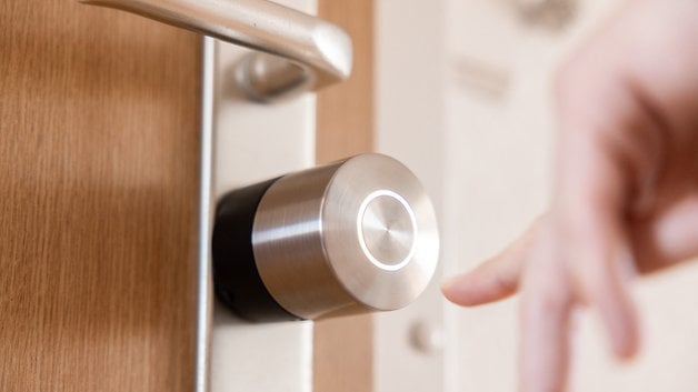 Ona yaklaşan bir el ile bir kapıya bir Nuki Smart Lock Pro'yu kapatın.