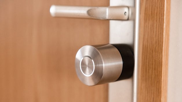 Ahşap bir kapıya monte edilmiş bir Nuki Smart Lock Pro'nun kapatılması.