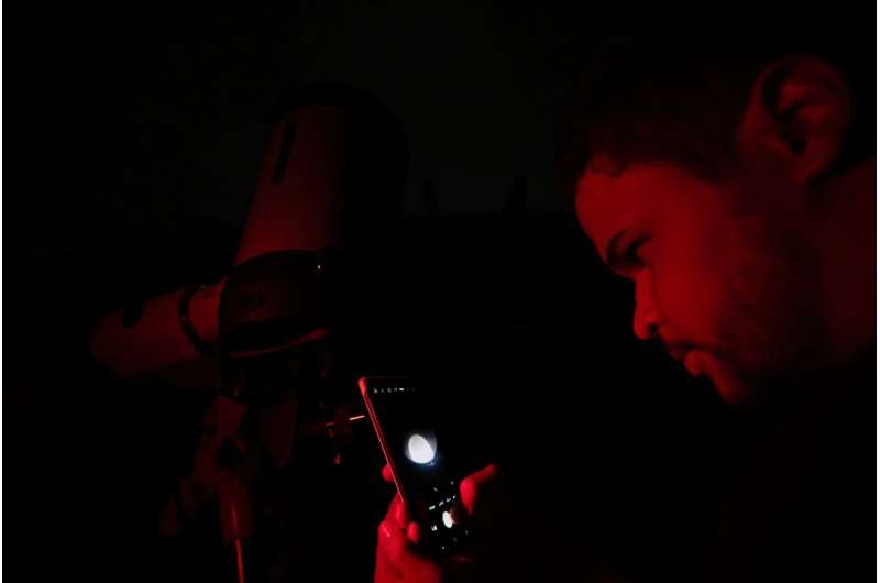 Bir adam, 14 Mart 2025'te Belo Horizonte, Brezilya'daki bir teleskop aracılığıyla telefonuyla 'Blood Moon'u fotoğraflıyor.