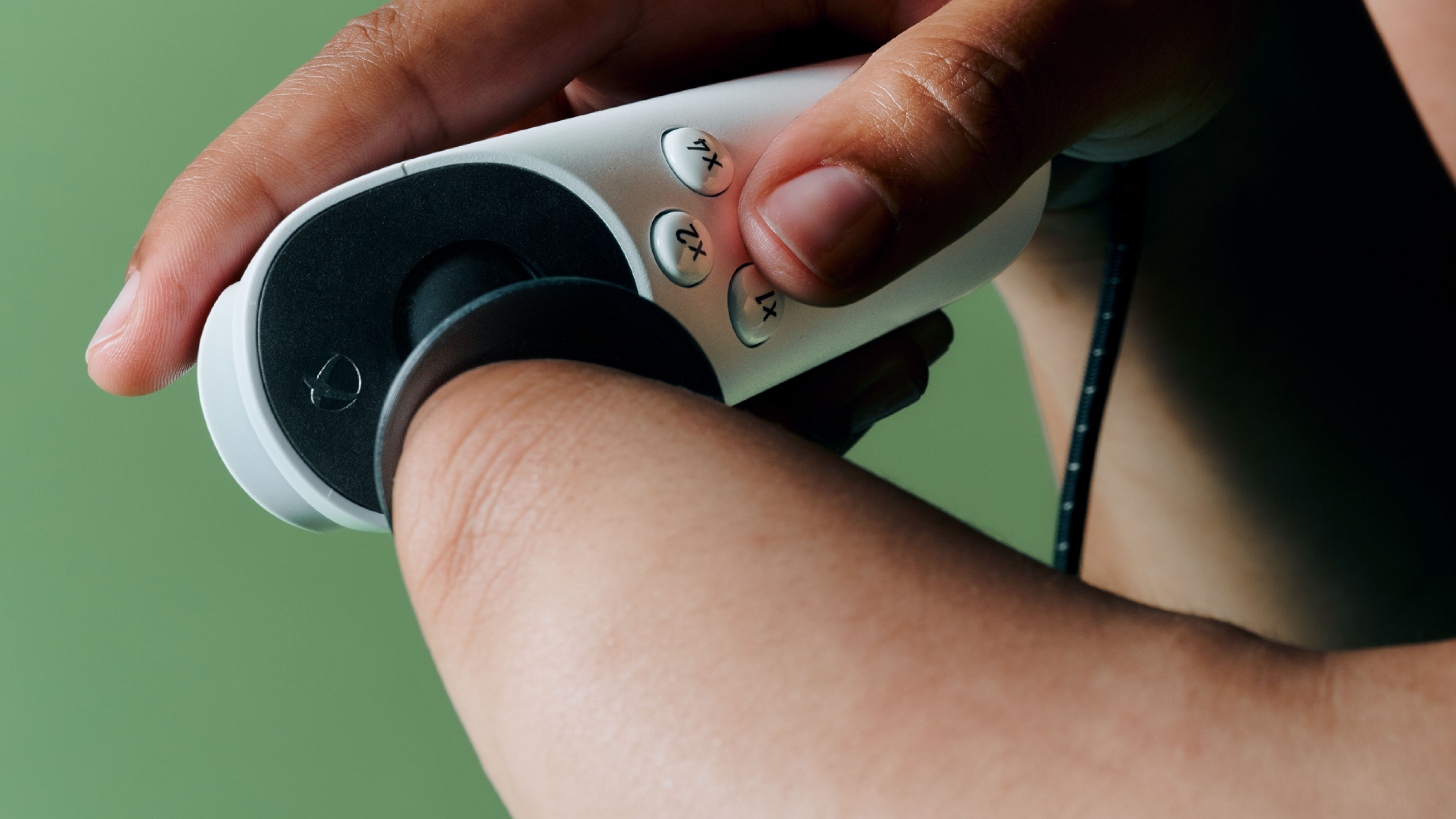 En içbükey kavrama ile Xbox uyarlanabilir joystick, kolunu kontrol etmek için bileklerini kullanan bir oyuncu ve yüz düğmesi girişleri için ikinci bir el.