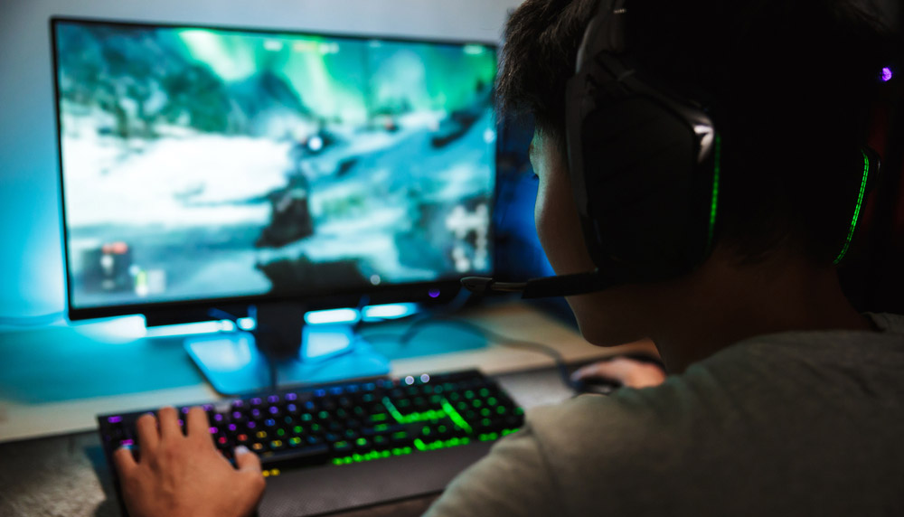 Bir RGB oyun klavyesi ve Logitech oyun kulaklığı kullanan bir PC oyuncusu.