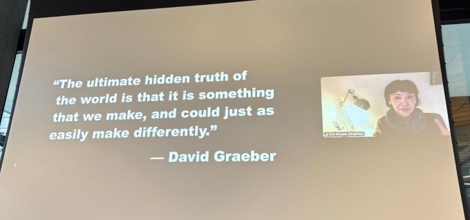 Erin Kissane'nin atmosfer konferansında uzaktan konuşan bir fotoğrafı, David Graeber'ın alıntısının yanında büyük bir ekranda görüldü.