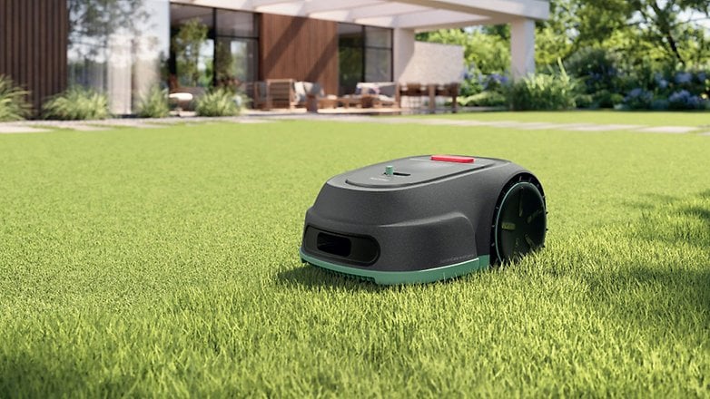 Modern bir evin önünde yeşil çimlerde Philips Çim Masabı Robotu.
