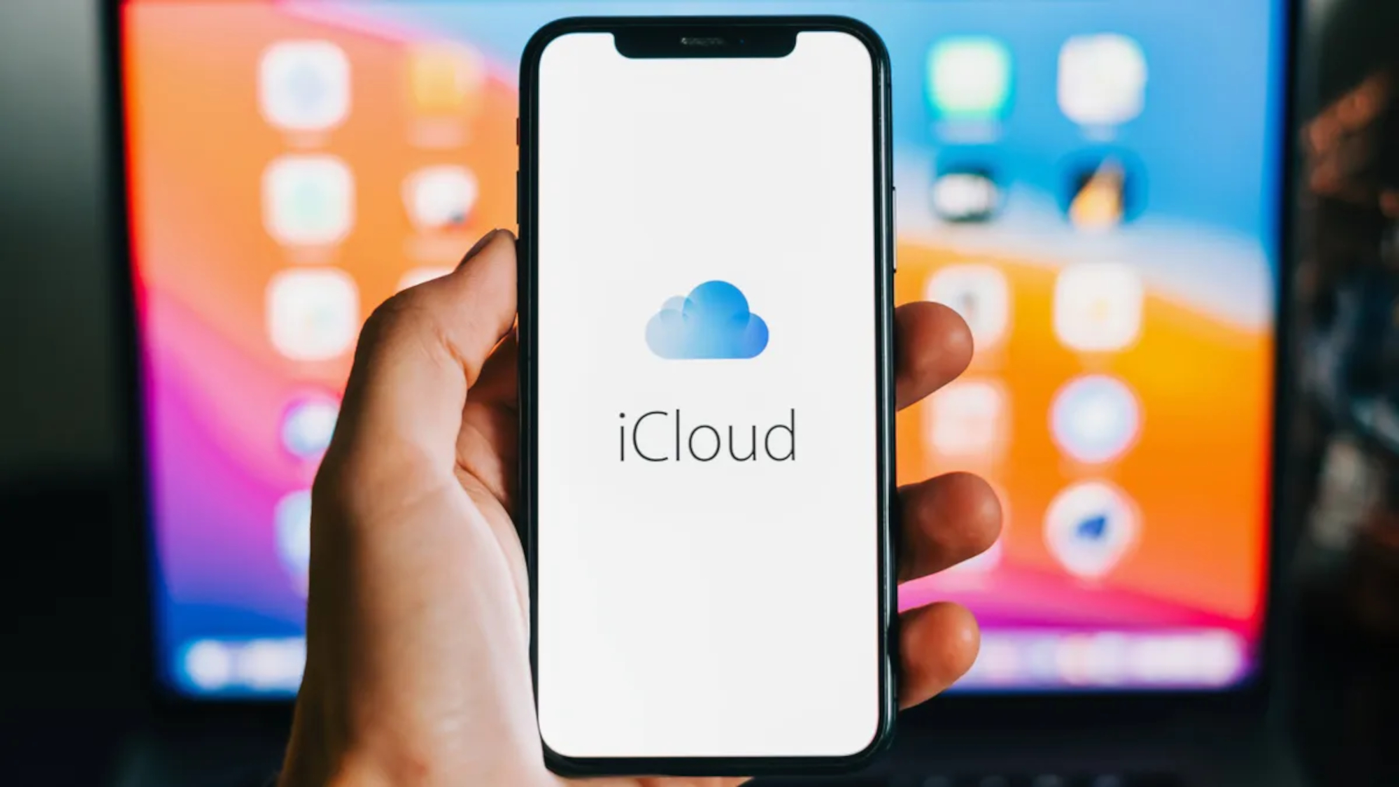 Ekranda iCloud logosu olan bir iPhone Mac'in önünde tutuluyor