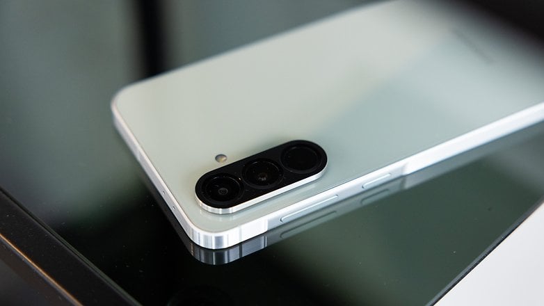 Bir Samsung Galaxy A56 akıllı telefon, cam yüzeyde bulunur ve kamera modülünü ve zarif tasarımını gösterir.