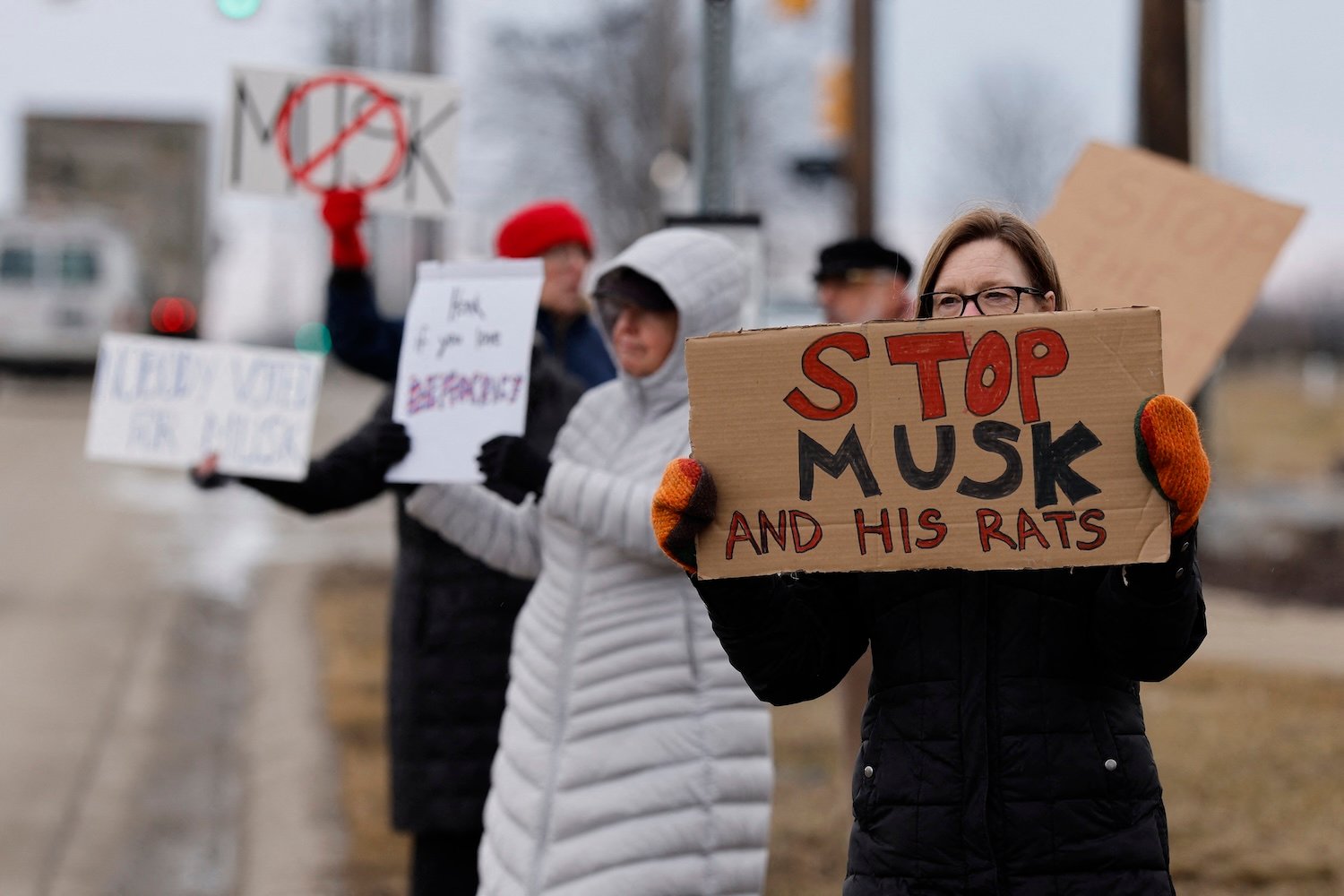 27 Şubat 2025'te Michigan, West Bloomfield'daki bir Tesla bayisinin dışındaki Elon Musk'a karşı bir protesto sırasında insanlar işaretler tutuyor
