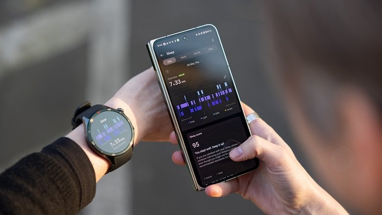 Bir kişi bileğe bir OnePlus saat giyerken bir akıllı telefondaki uyku verilerini kontrol eder.