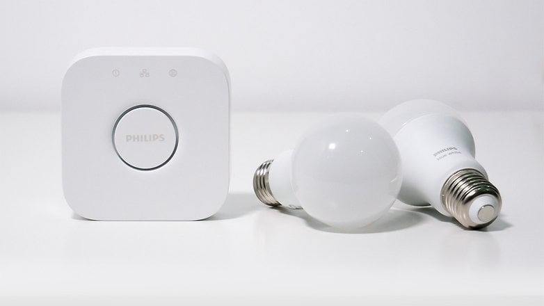 Philips Hue Köprüsü ve beyaz bir yüzeyde iki beyaz akıllı ampul.