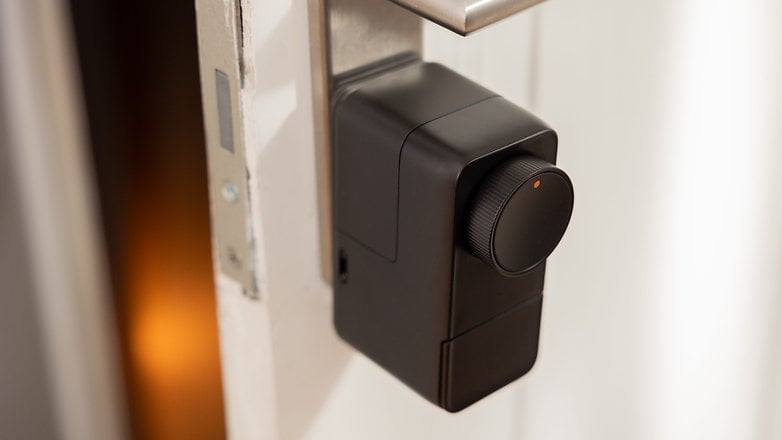 Siyah tasarım ve dönen bir düğmeye sahip bir kapıya bağlı bir Switchbot Lock Pro akıllı kilidi.