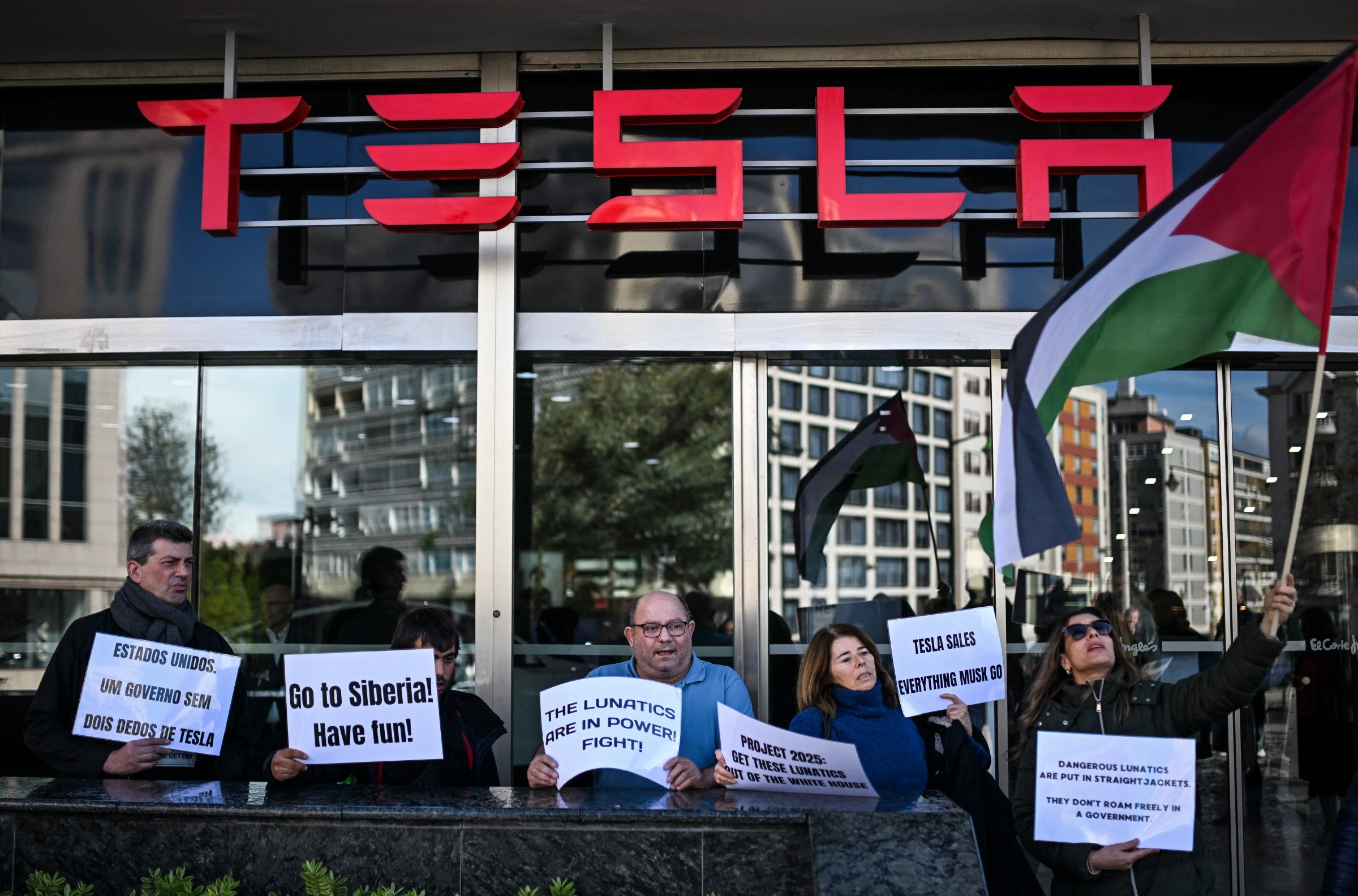 Göstericiler Tesla'nın Lizbon'daki bayisine işaretler tutuyorlar.