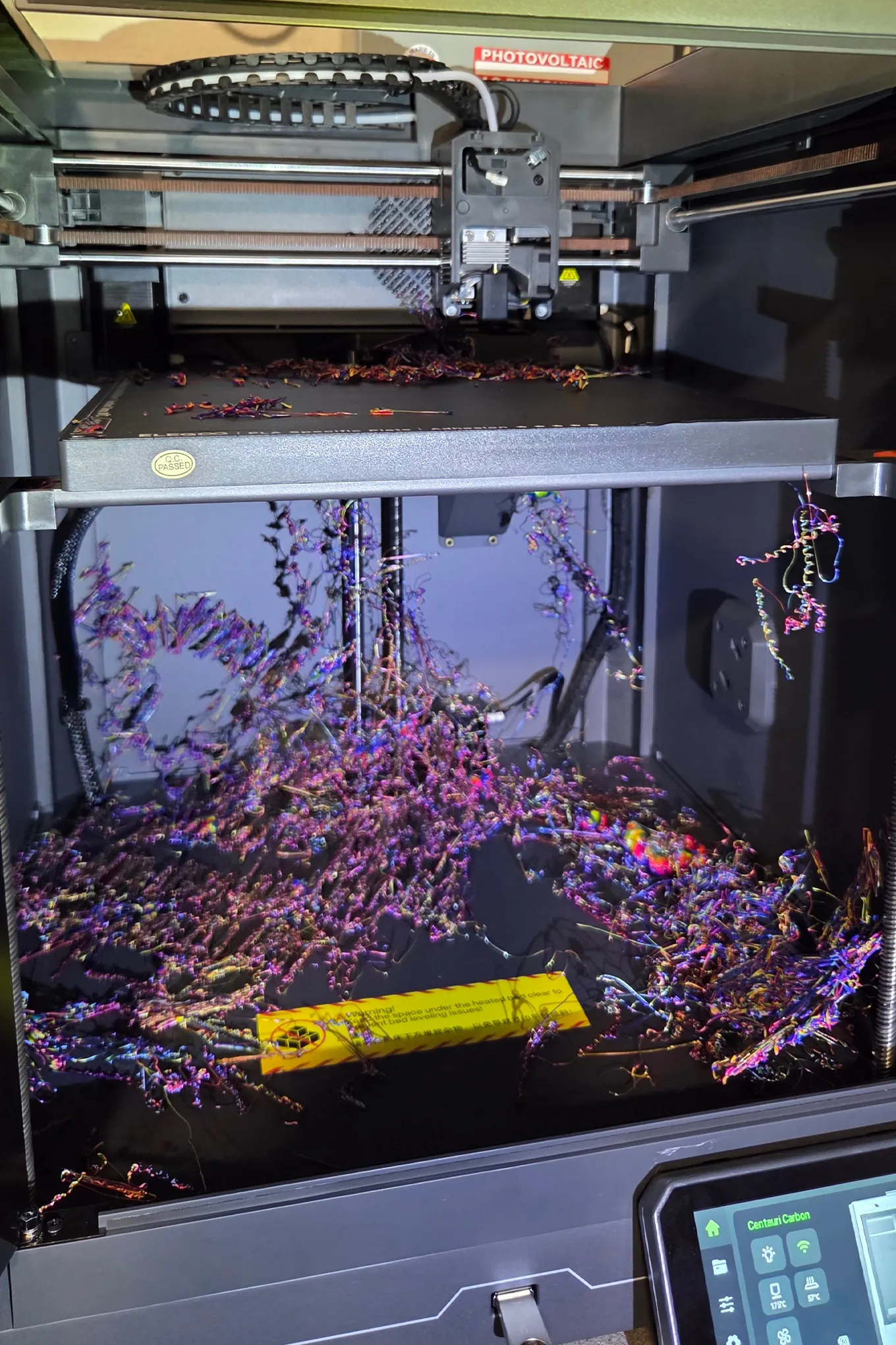 3D yazıcının kutusunun içinde, birçok renkli filament dağınık bir şekilde yıpranmış halde bulunuyor.
