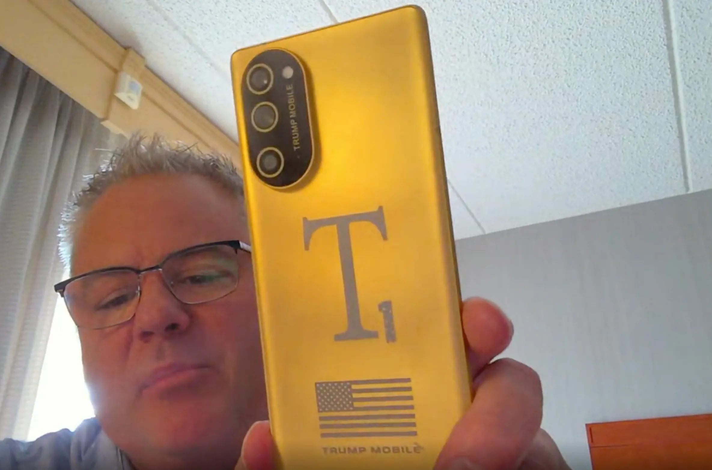 Eric Thomas'ın Trump Mobile ile altın T1 Telefonunu webcam'ine doğru tuttuğu ekran görüntüsü