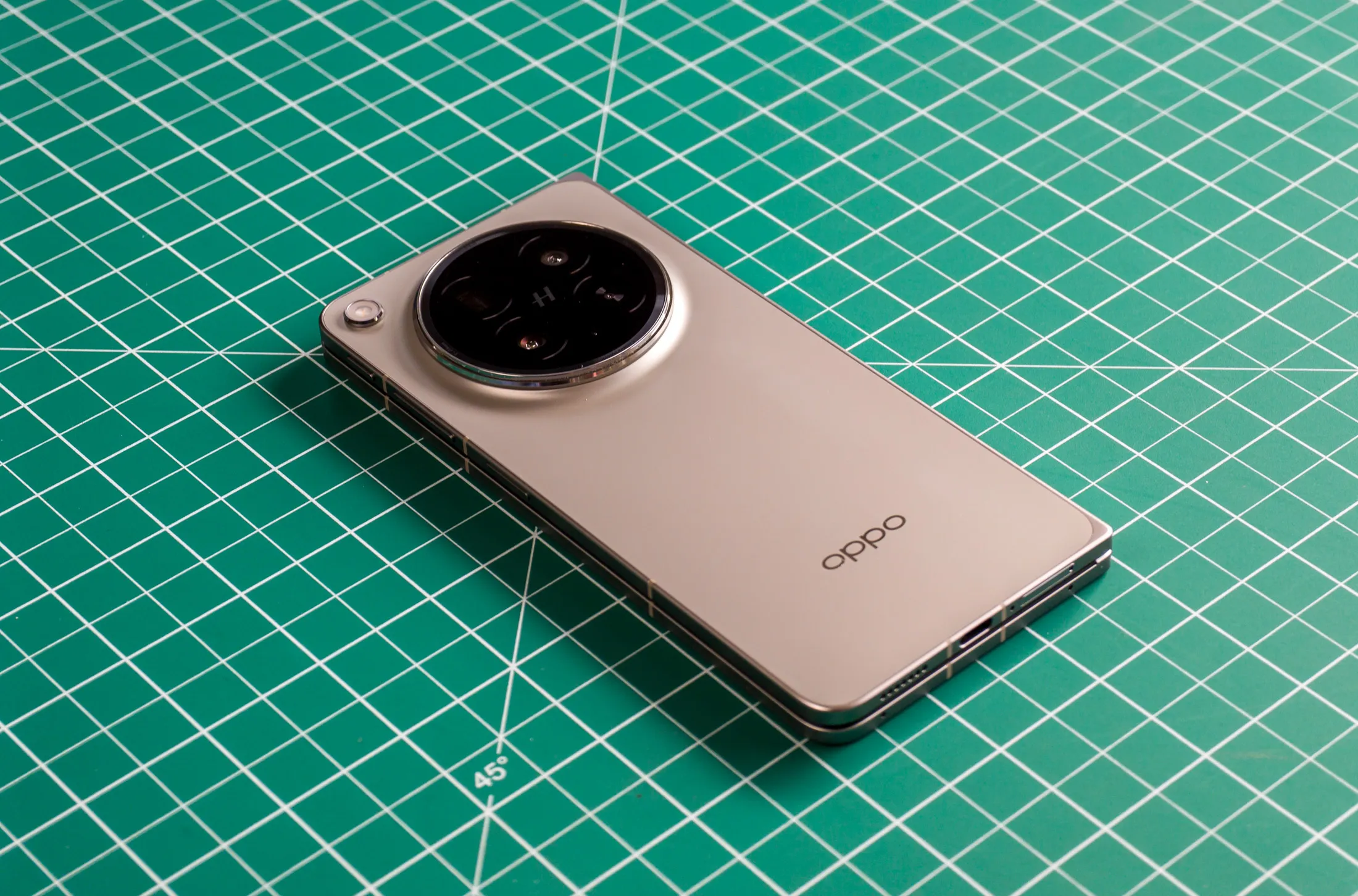 Oppo Find N6'nın yeşil bir iş matı üzerinde kapalı ve arkası yukarıda resmedilmiş