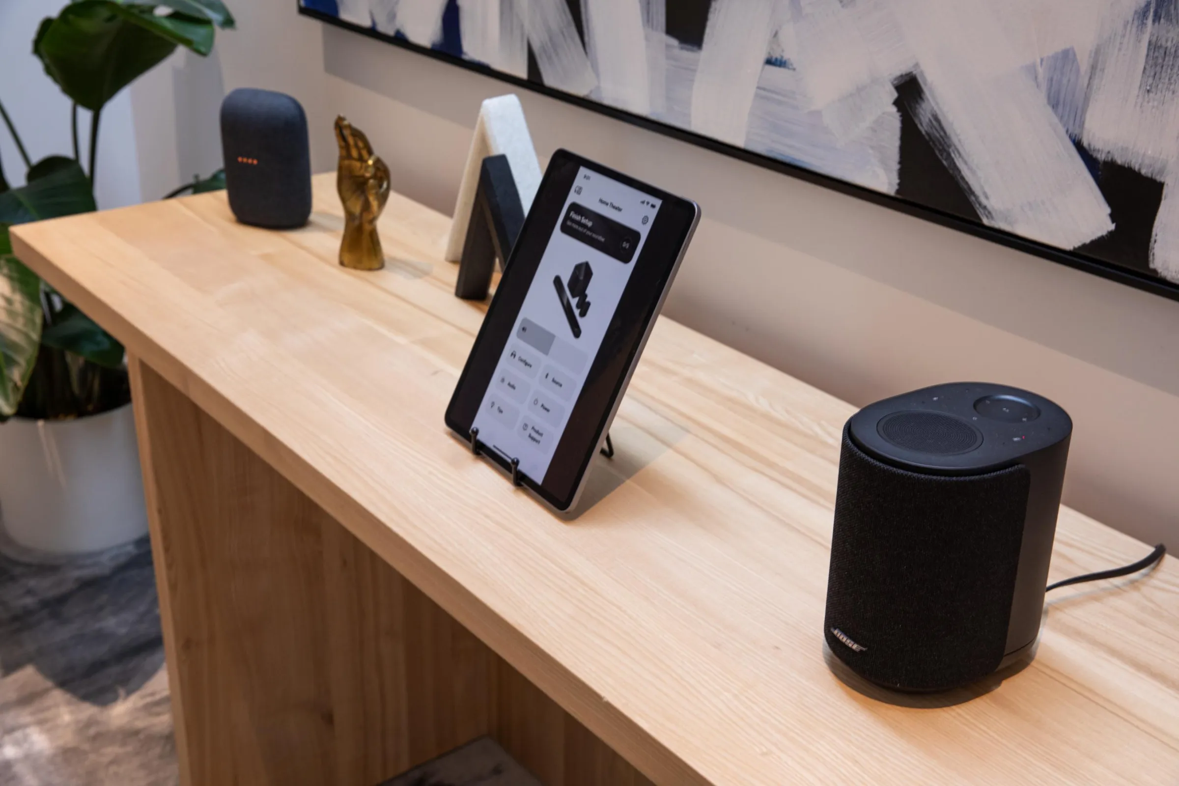 Bose Ultra Hoparlör, ahşap bir masanın üstünde bir tablet ve Google Nest hoparlörü ile yan yana.