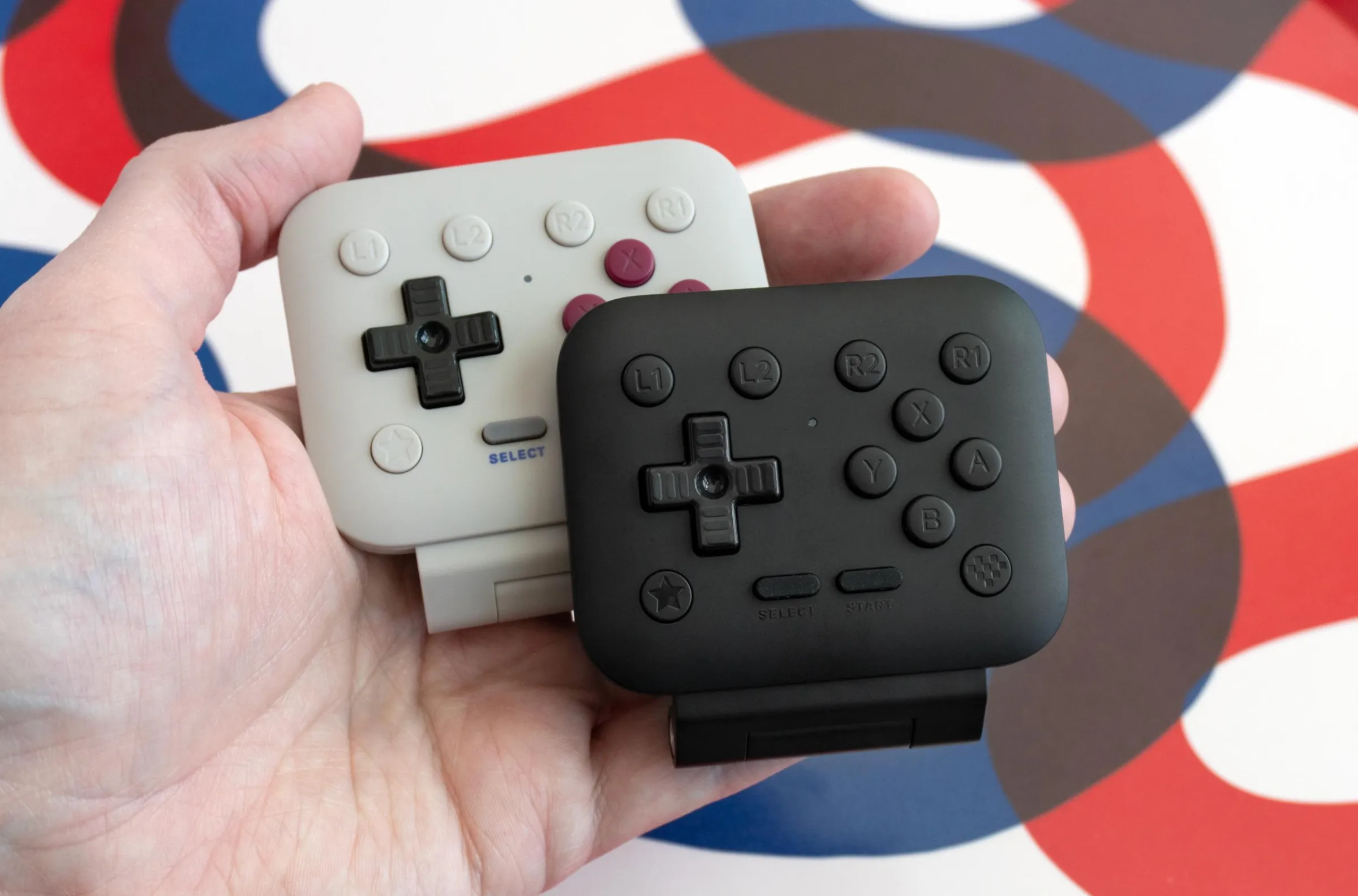 Bir kişi, 8BitDo FlipPad'ın iki farklı renk versiyonunu tutuyor.